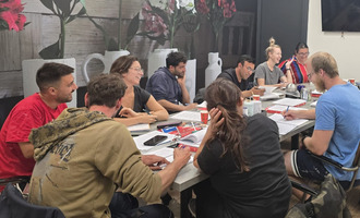 Een groep oefent samen aan een tafel